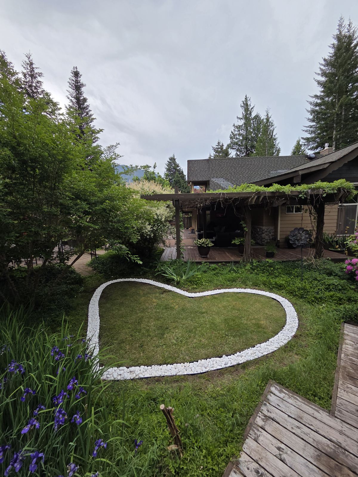 White rock lawn border in a heart shape with house and pergola behind